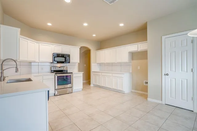 a kitchen with white cabinets and appliances