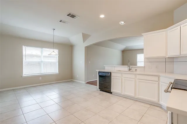 a view of an empty room with cabinet and window