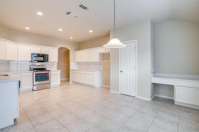 an empty room with chandelier fan and windows