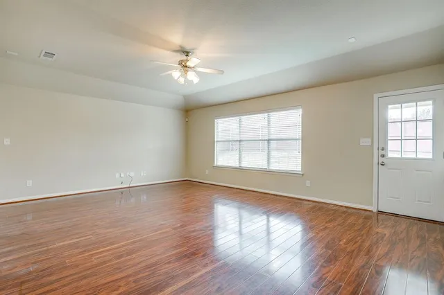 a view of an empty room with wooden floor and a window
