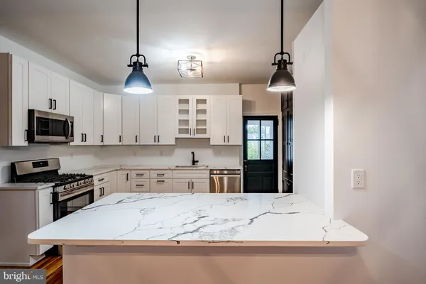 a kitchen with kitchen island granite countertop stainless steel appliances a stove sink and microwave