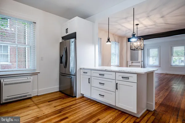 a kitchen with stainless steel appliances granite countertop a refrigerator a oven and white cabinets with wooden floors