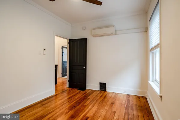 an empty room with wooden floor cabinet and windows