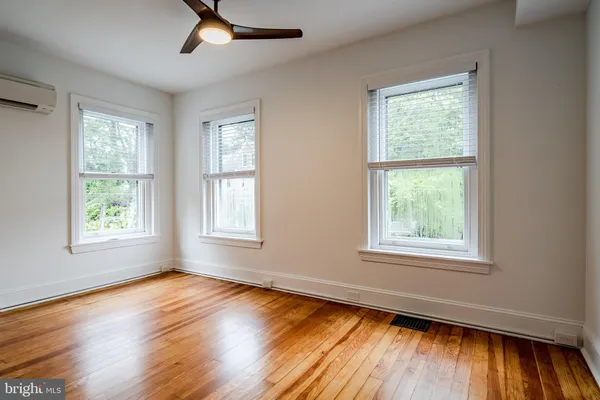 an empty room with wooden floor cabinet and windows