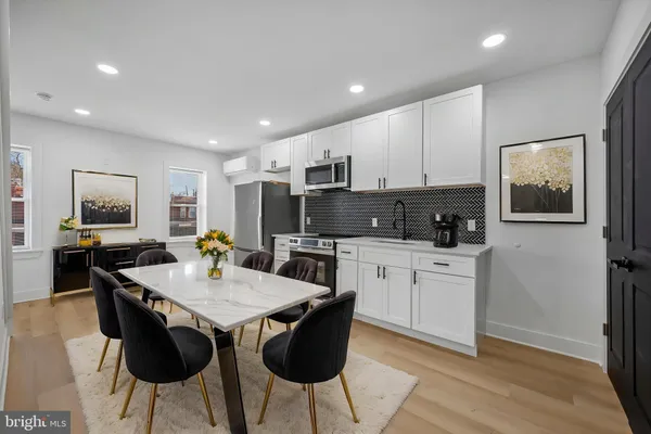 a kitchen with stainless steel appliances granite countertop a stove a sink a microwave a dining table and chairs with wooden floor