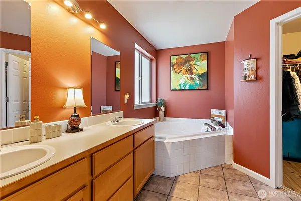 a bathroom with a double vanity sink a mirror and a bathtub