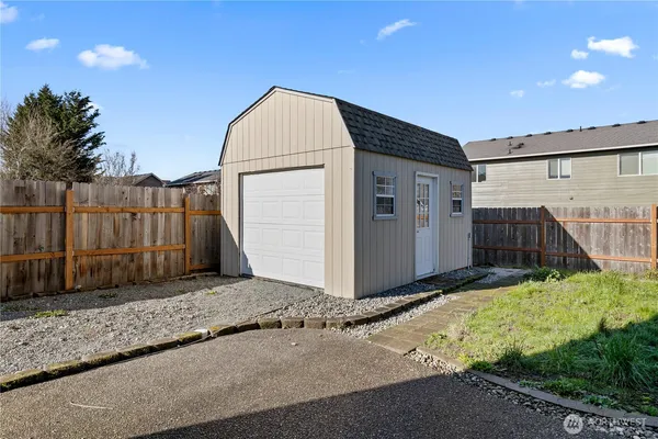 a view of a small space in front of a house with wooden fence