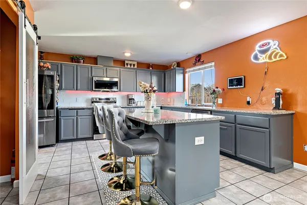 a kitchen with stainless steel appliances a sink a stove a refrigerator cabinets and a dining table
