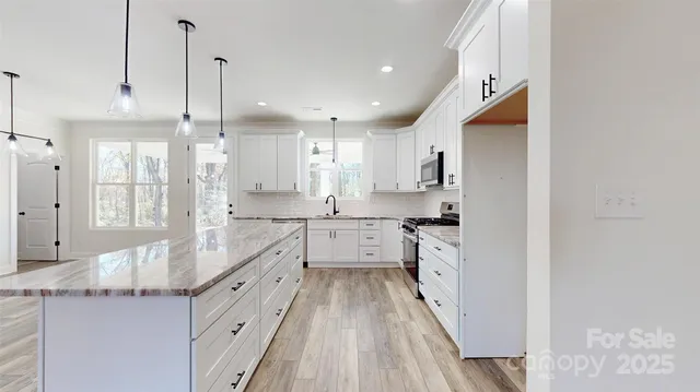 a large kitchen with kitchen island white cabinets and stainless steel appliances