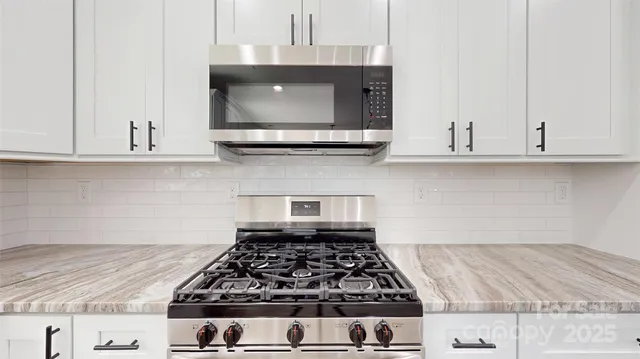 a kitchen with granite countertop white cabinets and stainless steel appliances