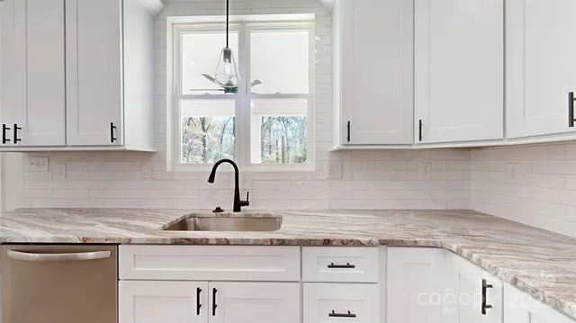 a kitchen with granite countertop white cabinets and a window