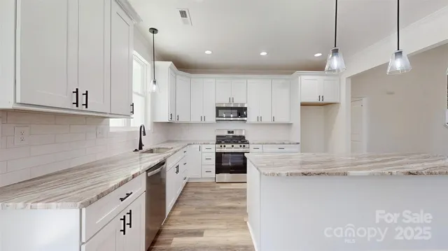 a kitchen with kitchen island granite countertop lots of white stainless steel appliances