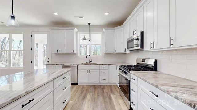 a kitchen with granite countertop cabinets stainless steel appliances a sink and a window