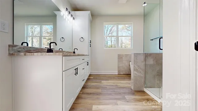a spacious bathroom with a double vanity sink a mirror and a shower
