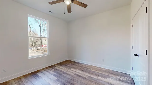a view of an empty room with window and wooden floor
