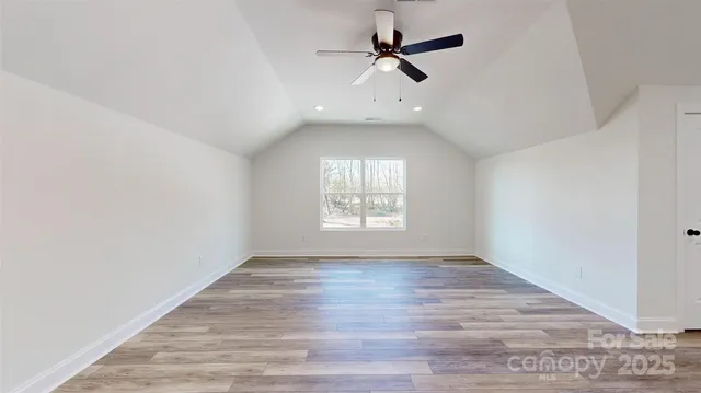an empty room with wooden floor ceiling fan and windows