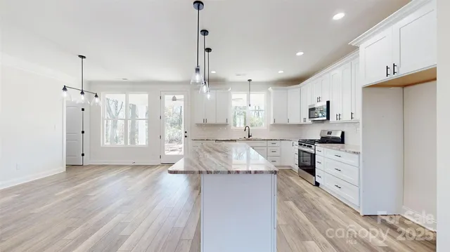 a large kitchen with kitchen island white cabinets and stainless steel appliances