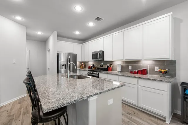 a kitchen with kitchen island granite countertop a table chairs microwave and cabinets