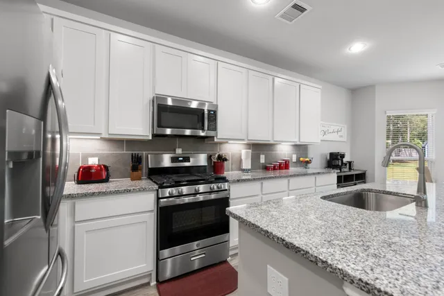 a kitchen with granite countertop a sink dishwasher stove and cabinets with wooden floor