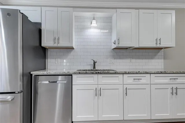 a kitchen with white cabinets and a refrigerator