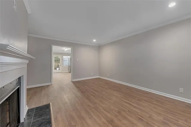 a view of an empty room with wooden floor and a fireplace