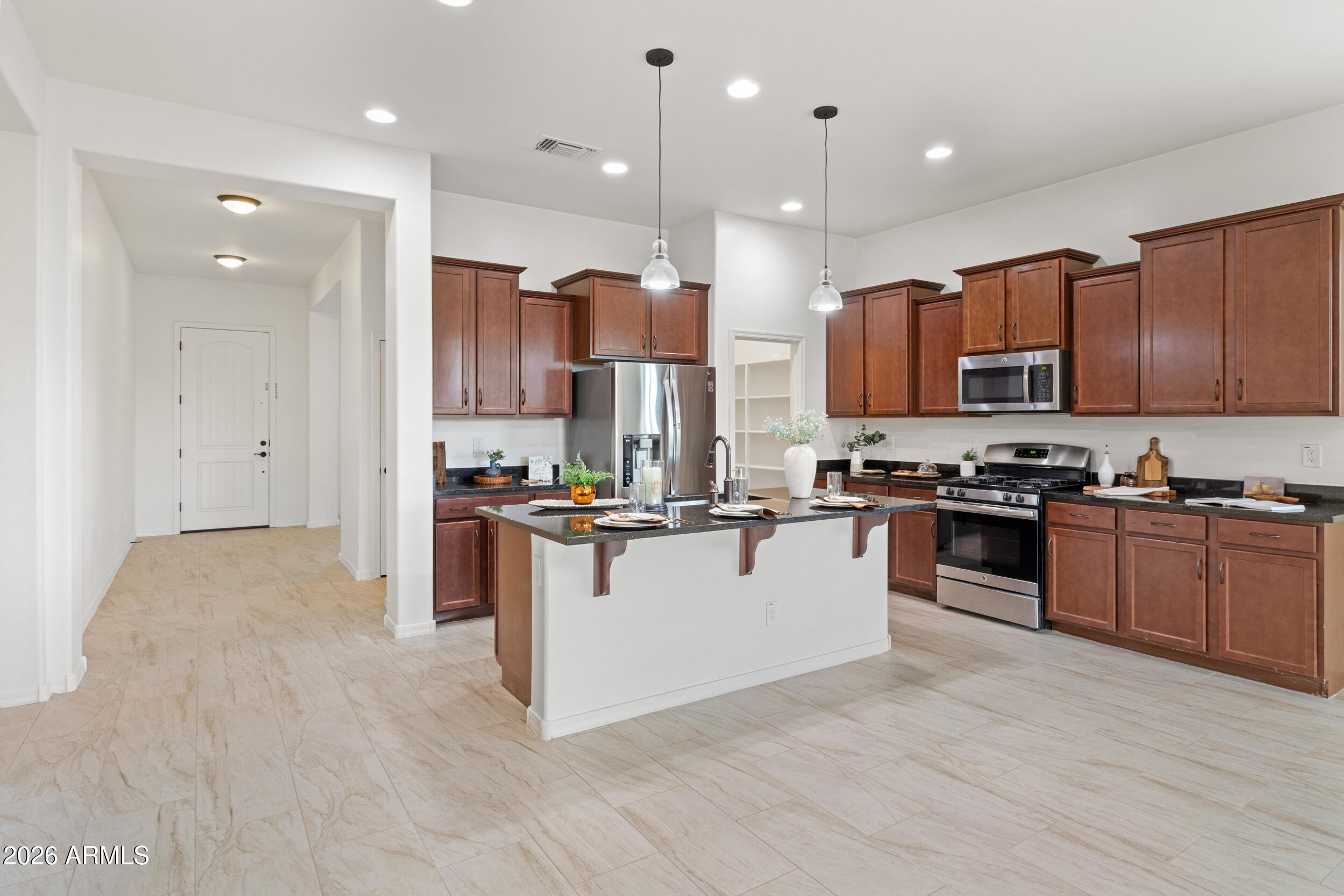 20537 West Valley View Drive Buckeye, AZ 85396 - Photo 5 of 32 a kitchen with stainless steel appliances kitchen island granite countertop a stove top oven a sink and a microwave
