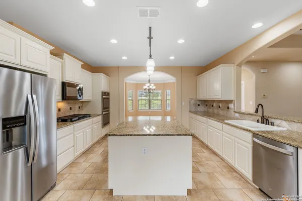 a large kitchen with granite countertop a large stove top oven a sink dishwasher and a refrigerator