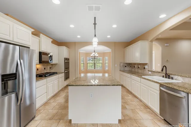 a large kitchen with granite countertop a large stove top oven a sink dishwasher and a refrigerator