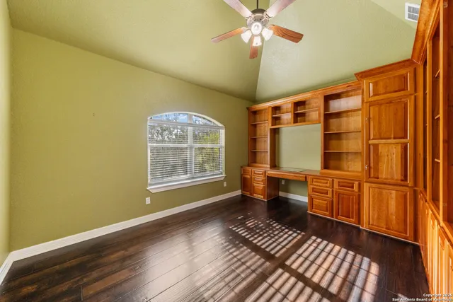 a view of an empty room with a window and wooden floor