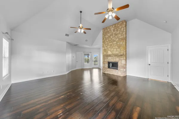 a view of an empty room with wooden floor fireplace and a window