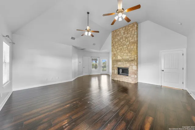 a view of an empty room with wooden floor fireplace and a window