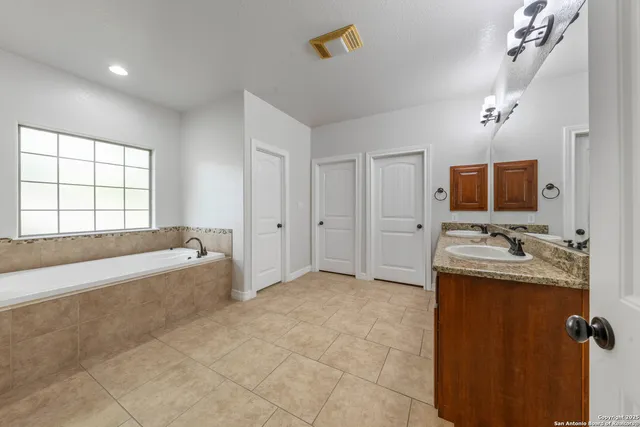 a spacious bathroom with a tub sink and mirror