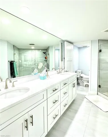 a spacious bathroom with double vanity a mirror and a shower