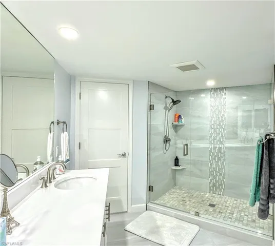 a bathroom with a granite countertop sink a shower and a mirror