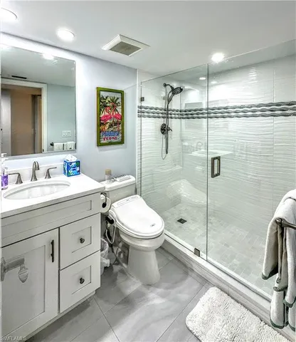 a bathroom with a toilet a sink a glass door a shower and a mirror