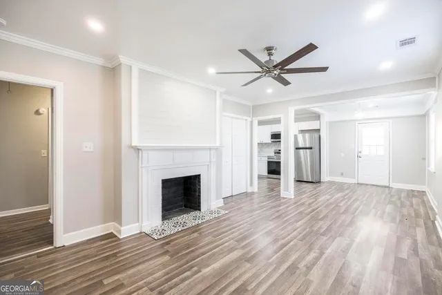 a view of an empty room with wooden floor fireplace and a window
