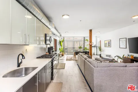 a large white kitchen with stainless steel appliances a sink a stove and a refrigerator