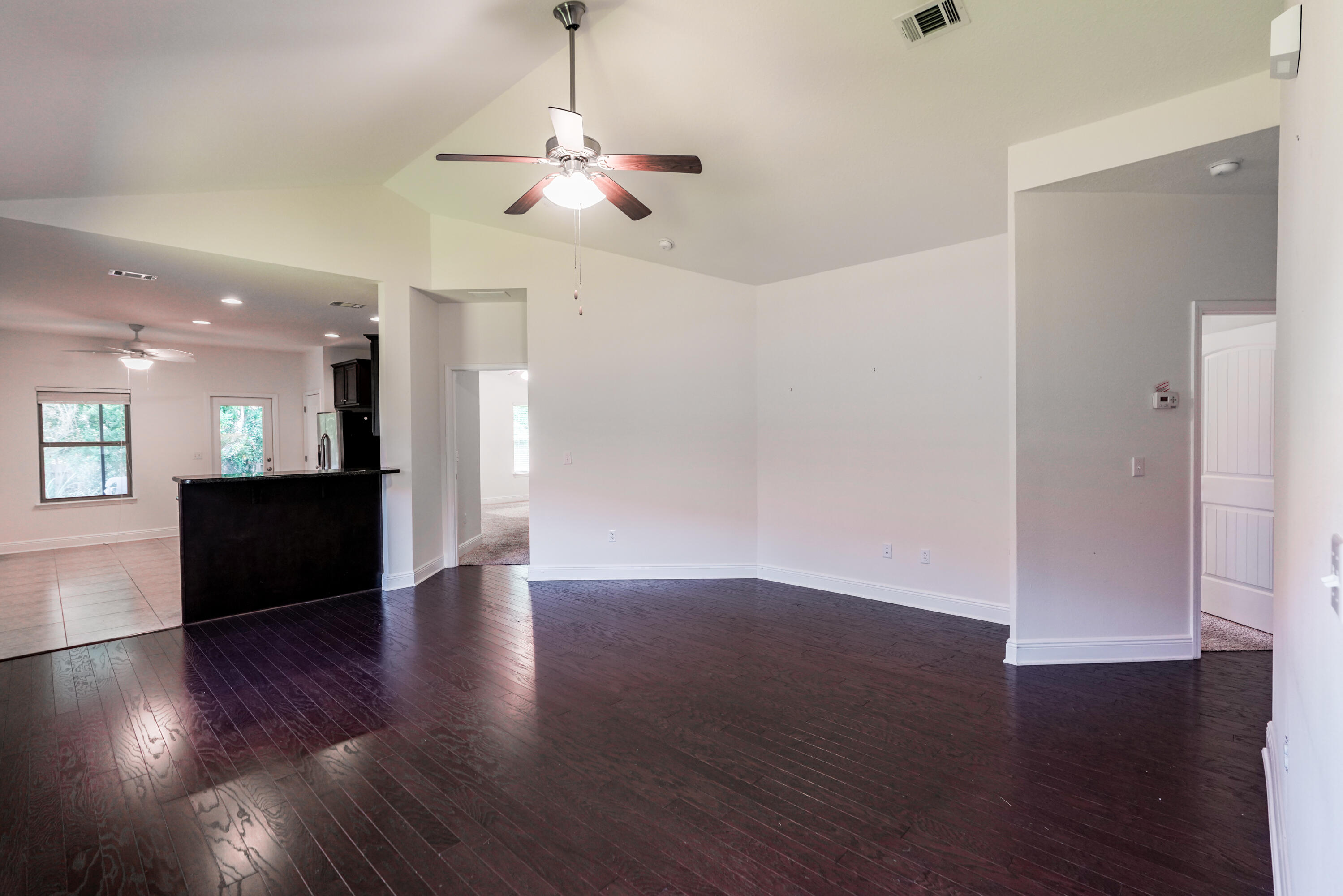 122 Riverbirch Loop Santa Rosa Beach, FL 32459 - Photo 4 of 41 a view of an empty room with wooden floor and a kitchen