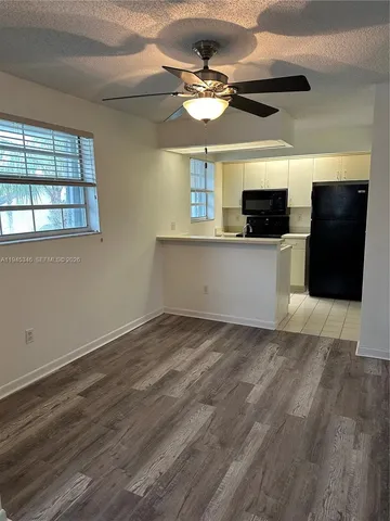 a view of kitchen with stainless steel appliances wooden floor and window