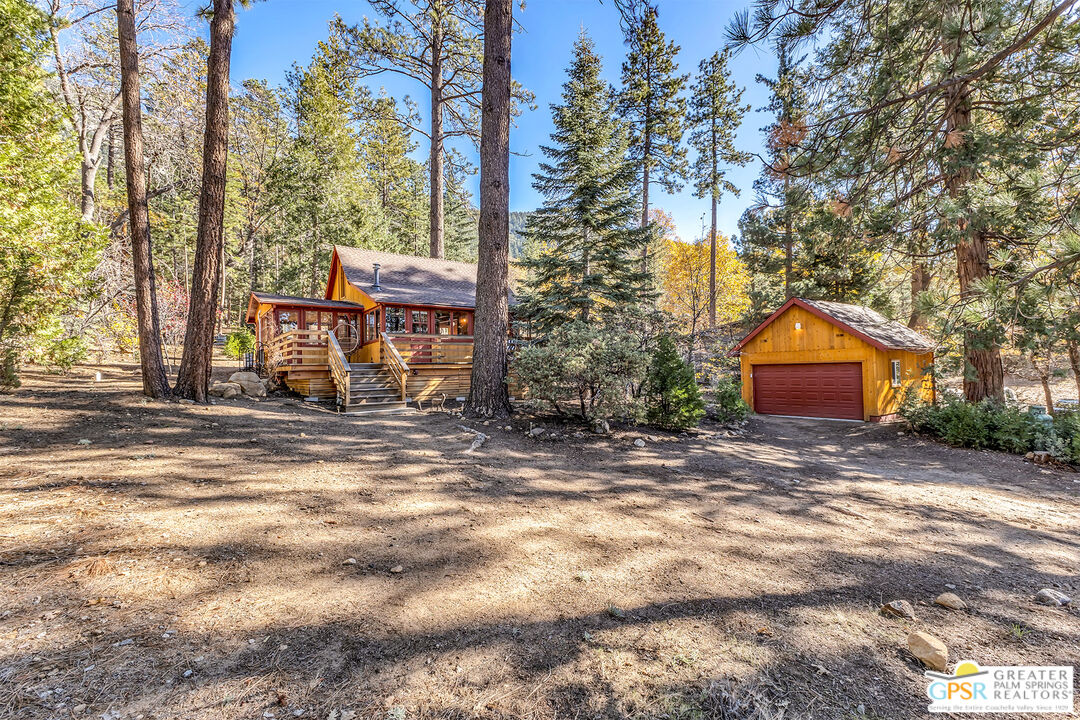 25250 Rim Rock Road Idyllwild, CA 92549 - Photo 58 of 72 a backyard of a house with large trees and outdoor seating
