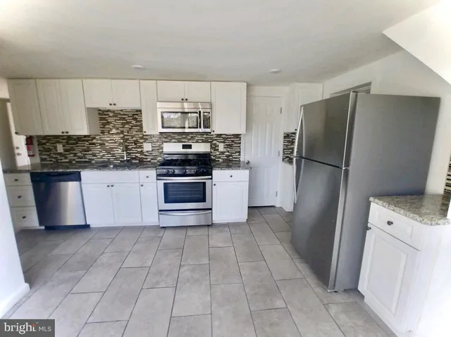 a kitchen with stainless steel appliances granite countertop a refrigerator stove and sink