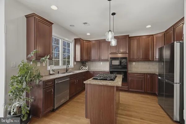 a kitchen with kitchen island granite countertop stainless steel appliances and wooden cabinets