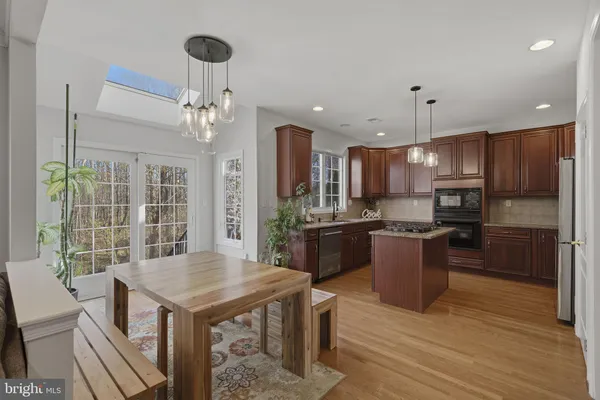 a kitchen with a refrigerator a sink dishwasher a dining table and chairs with wooden floor
