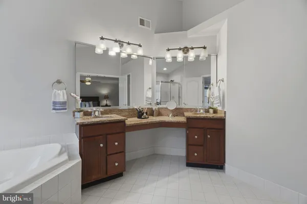 a large bathroom with a sink double vanity granite tub and a mirror
