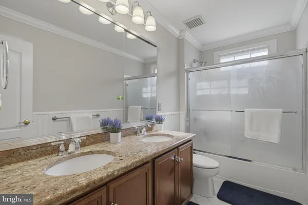 a bathroom with a granite countertop sink a toilet a mirror and shower