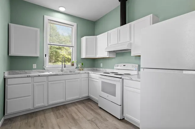 a kitchen with granite countertop white cabinets sink and white appliances