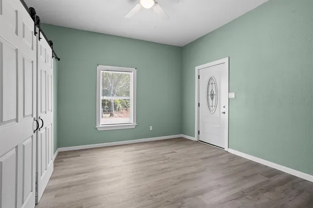 a view of an empty room with wooden floor and a window