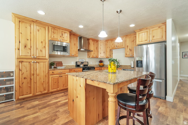 13038 Tower Ridge Drive Riverton, UT 84096 - Photo 9 of 30 Spacious kitchen featuring natural wood cabinetry, granite countertops, stainless steel appliances, and wood-finish flooring