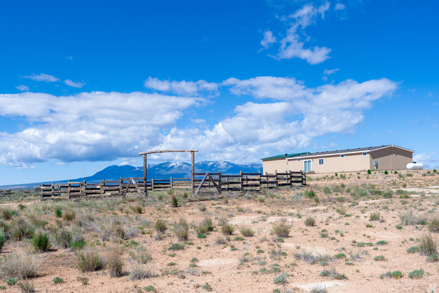 700 East Peter Springs Road Monticello, UT 84535 - Photo 41 of 57 Expansive desert landscape featuring a tan exterior residence with a green roof, a sliding glass patio door, and a propane tank