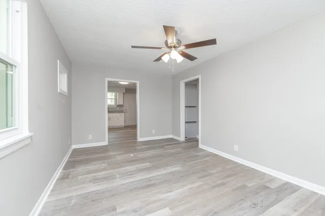 a view of empty room with wooden floor and fan